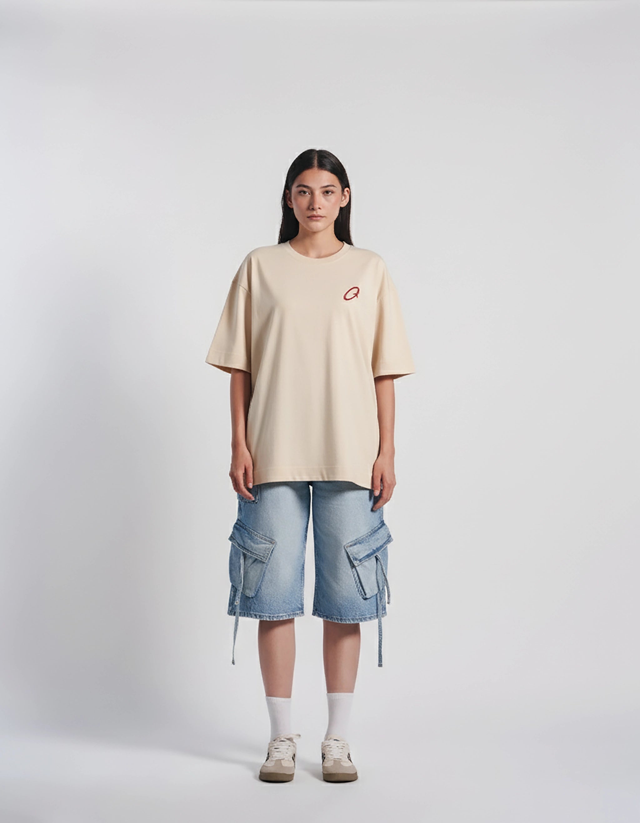 Person wearing a beige t-shirt and blue cargo shorts on a white background